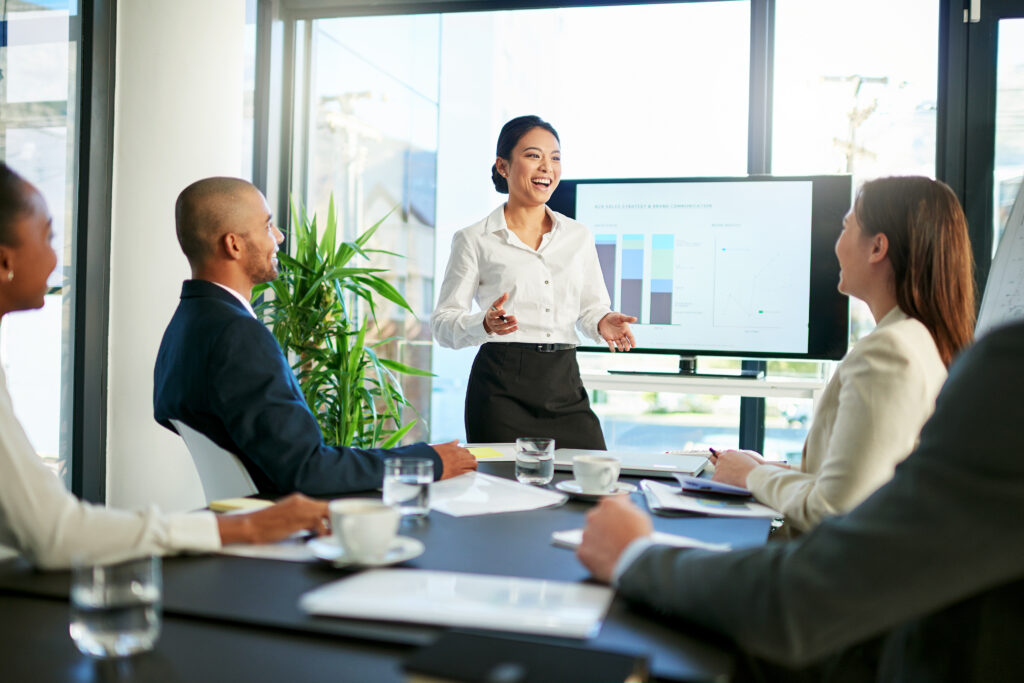 A young business professional presenting data charts on a screen to her colleagues.