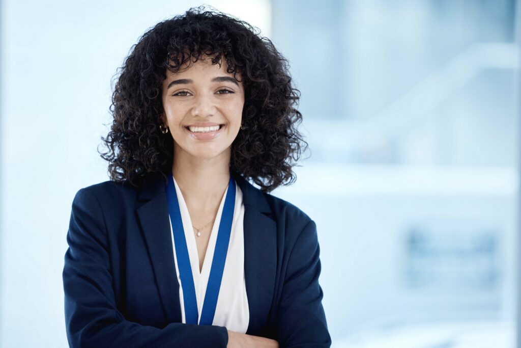 A smiling young professional standing inside a bright, modern office setting.